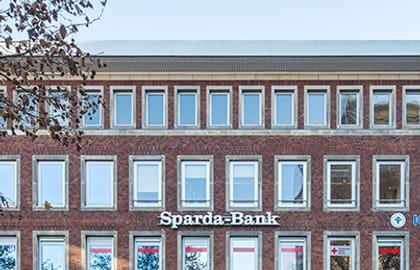 Viergeschossiges Backsteingebäude mit Bankfiliale im Erdgeschoss, davor eine lange Reihe abgestellter Fahrräder.